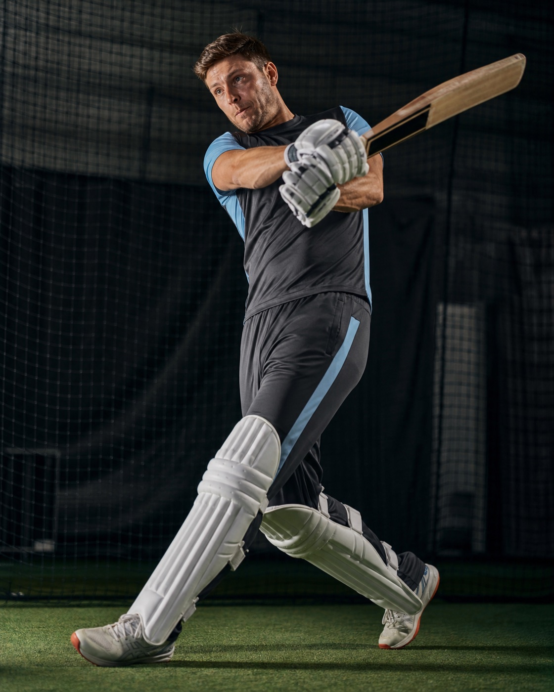 Cricketer batting in charcoal and blue training kit